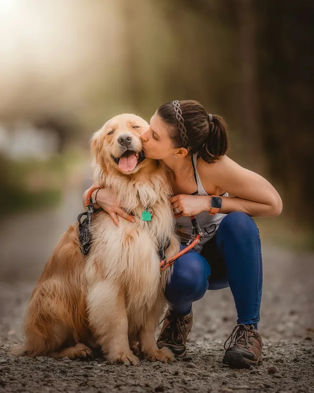 Tutora abraçando e beijando seu cão com carinho ao ar livre